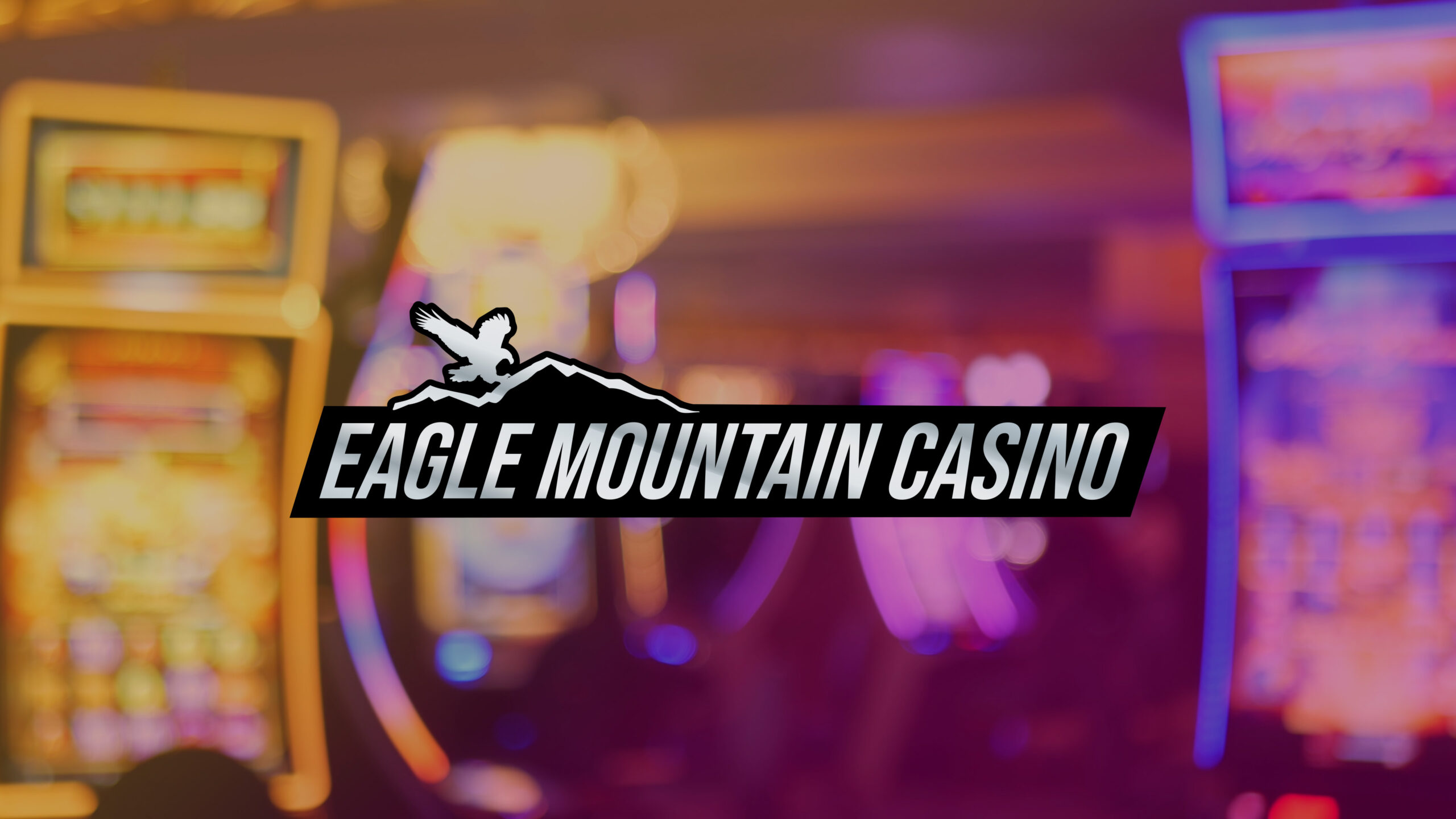 Eagle Mountain Casino logo on top of a blurred slot machine area of a casino