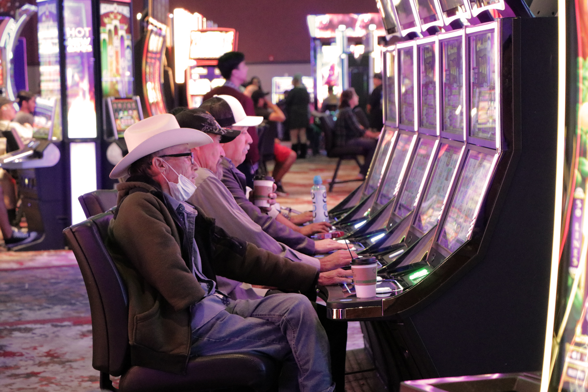 Three men sit in front of slot machines playing to win at Eagle Mountain Casino