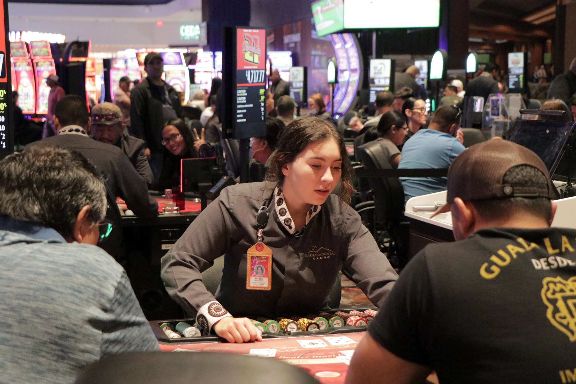 Facing an Eagle Mountain Casino dealer while two men sit at the table playing to win